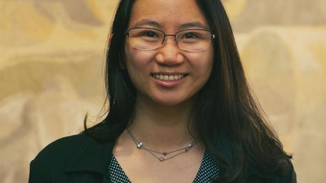 Professional headshot of Janice Lam wearing glasses and a dark blazer, smiling in front of a neutral background.