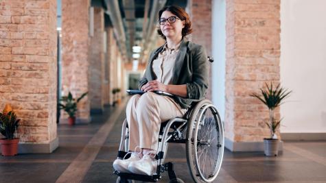 A person sitting in a wheelchair in front of brick walls. 