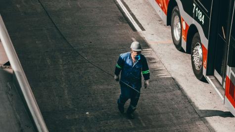 A person walking on a sidewalk beside a parked bus.