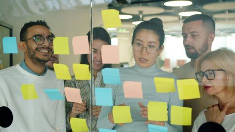 workers looking at different coloured post-it notes on a wall