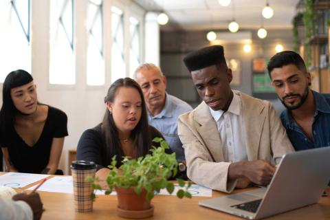 A diverse group of people looking at a laptop screen