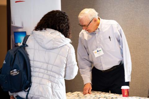 Two people looking at the welcome table to pick out name tags.