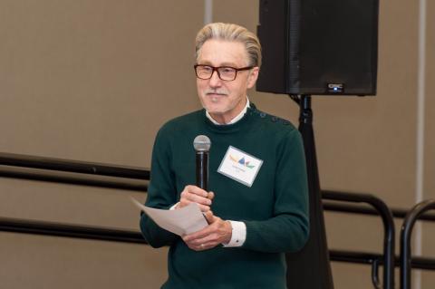 A person holding a piece of paper speaks into a microphone.