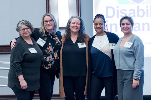 A group of five pose together for a picture. 