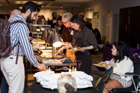 A line of people serve themselves at a buffet.
