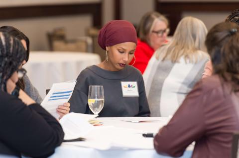 Three people sit at a table reading brochures. 