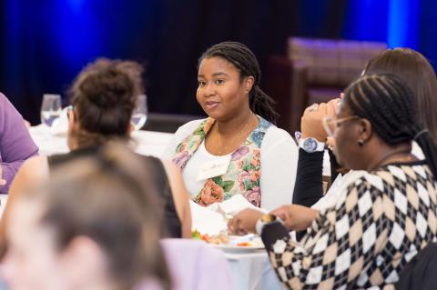 Four audience members at a table conversing. 