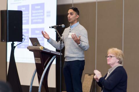Arif Jetha presents at the 2025 DWC Symposium with an ASL interpreter standing beside him providing ASL interpretation