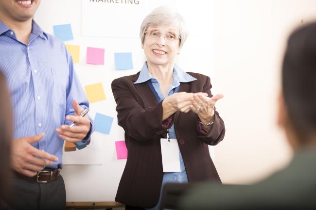 A speaker in a boardroom with an ASL interpreter beside them