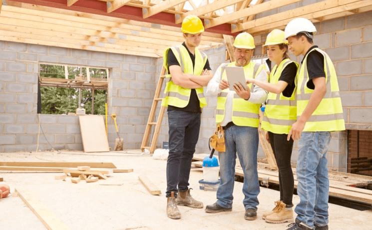 Young workers on a contruction job site, wearing high visibility vests and hard hats