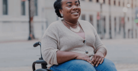 a woman in her wheelchair smiles in the street