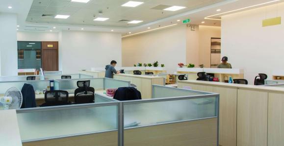 An office with cubicles sitting under florescent lights.