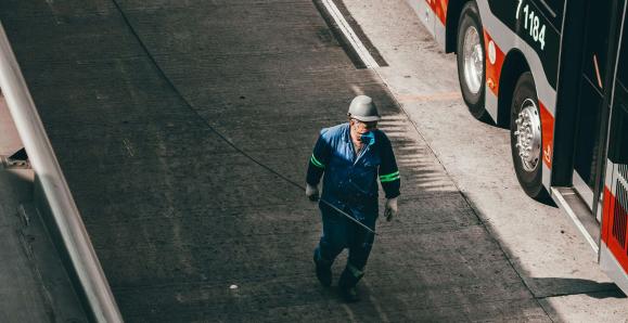 A person walking on a sidewalk beside a parked bus.