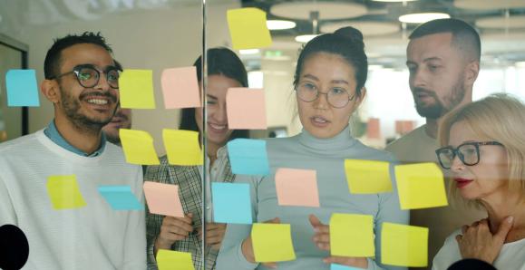 people looking at post-its on a glass wall