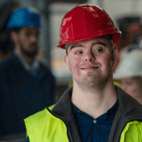person with Down syndrom in a hard hat and safety vest