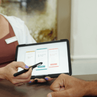 a woman presenting pricing options to a customer using their tablet