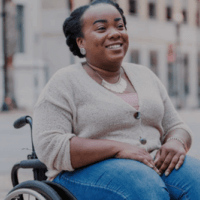 a woman in her wheelchair smiles in the street