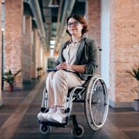 A person sitting in a wheelchair in front of brick walls. 