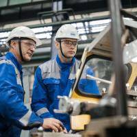 manufacturing workers wearing hardhats and blue jumpsuits 