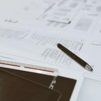 Top view of architectural blueprints, pen, and scale ruler on a designer's desk, showcasing a creative workspace